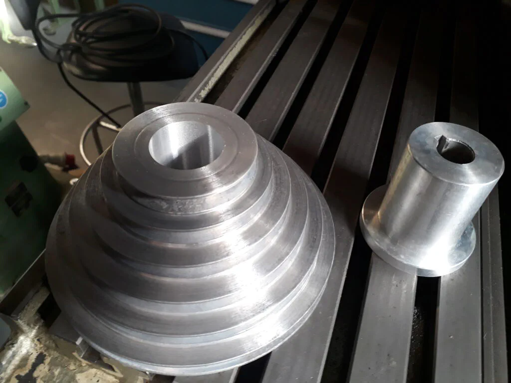 Una politja d'alumini al costat d'un nucli cilíndric